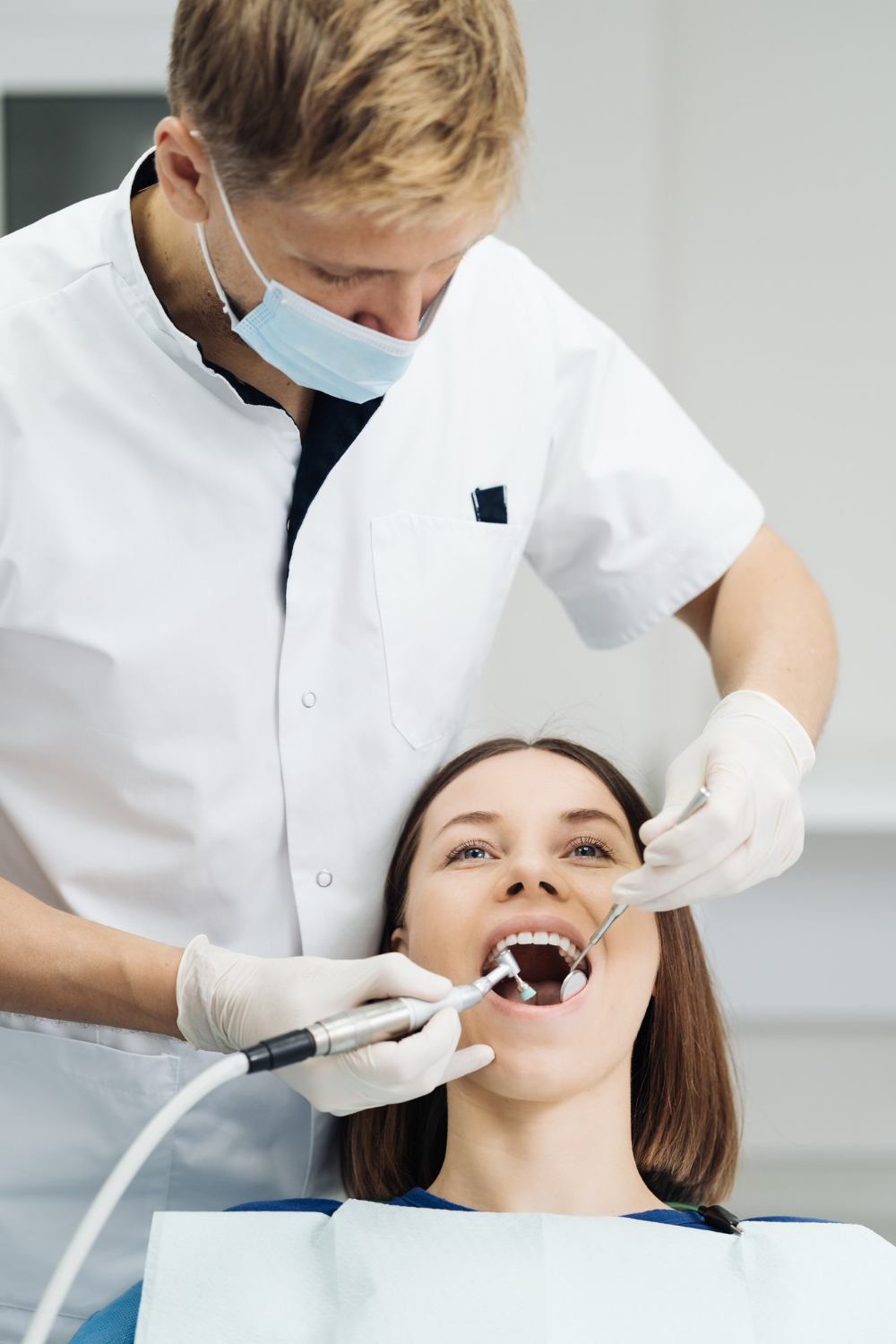 Young female dentist treating patients teeth with dental microscope dentistry concept